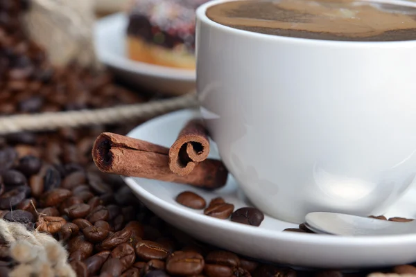 ジュートのヘシアンの背景の上にカップとロースト コーヒー豆 — ストック写真