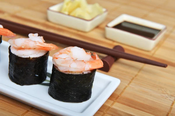 Prato com rolos de sushi frescos em fundo de guardanapo de bambu — Fotografia de Stock