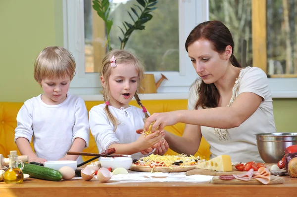 Madre con niños cortan verduras para pizzas —  Fotos de Stock