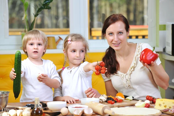 Mother with children cut vegetables for pizzas — Stock Photo, Image