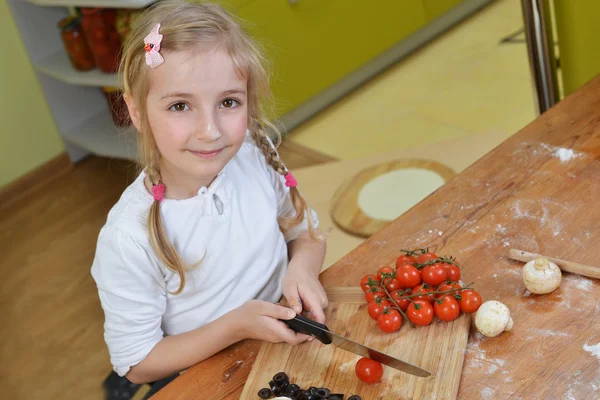 Klein meisje gesneden groenten voor pizza 's — Stockfoto