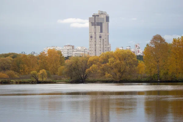 Moderní městské budovy po řece a Les na podzim — Stock fotografie