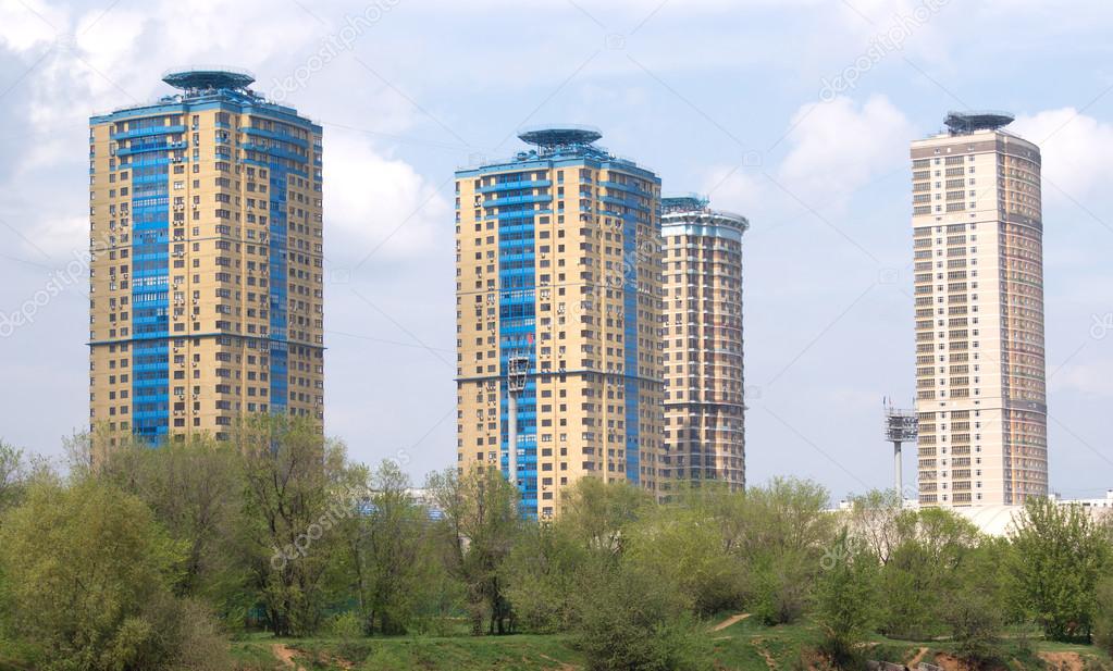 City landscape with high modern apartment buildings on blue sky with clouds