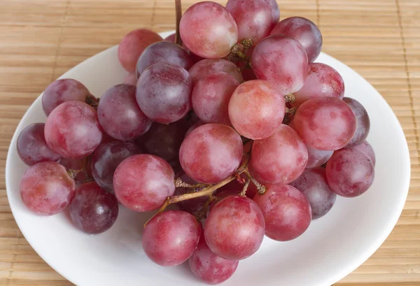 Ramo de uva vermelha na placa redonda branca — Fotografia de Stock