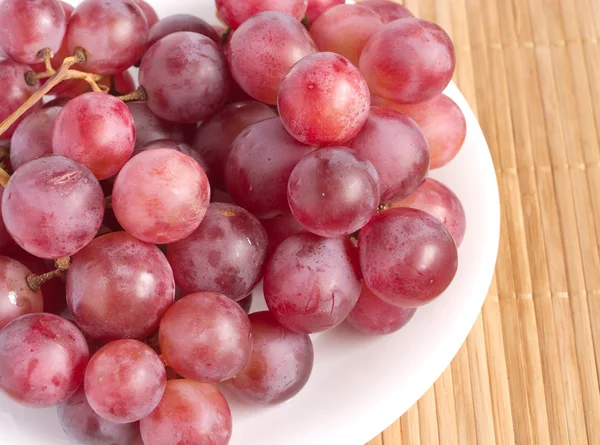 Rote Traubenbeeren in weißem Teller auf Stroh Tablett Nahaufnahme — Stockfoto