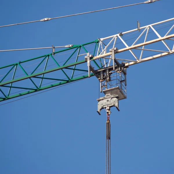 Construção verde e branco guindaste içamento parte sobre céu azul claro sem nuvens — Fotografia de Stock