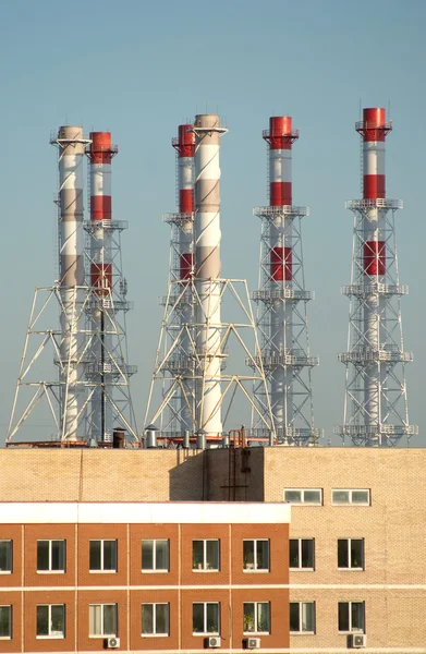 Industrial building and many smoke pipes after it over blue sky — Stock Photo, Image