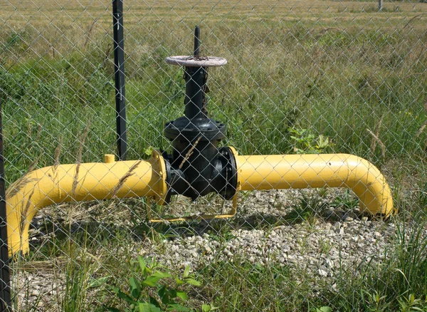 黄色燃气管道与水龙头后在农村中的栅栏 — 图库照片