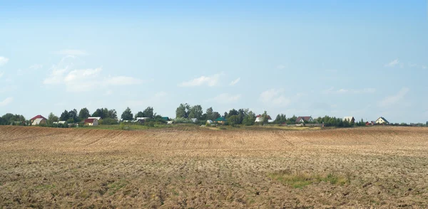 Landschaft mit Ackerland und einem Dorf in weiter Ferne — Stockfoto