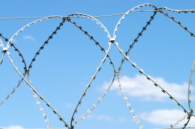 Beyaz bulutlar gökyüzü üzerinde bükümlü tel dikenli