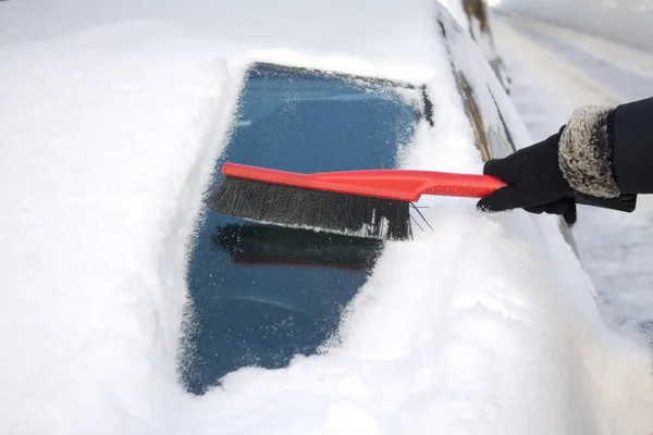 Donna spazzolando la neve da una macchina — Foto Stock