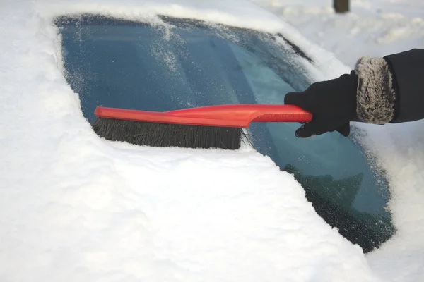 Donna spazzolando la neve da una macchina — Foto Stock