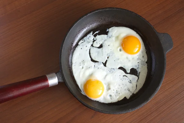 Fried eggs in black pan closeup — Stock Photo, Image