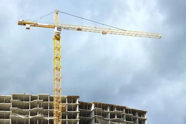 Tower crane above top of building over stormy sky — Stock Photo, Image