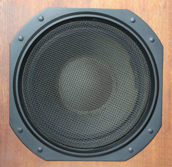 Subwoofer Loud speaker system with round black grill and wooden finish closeup