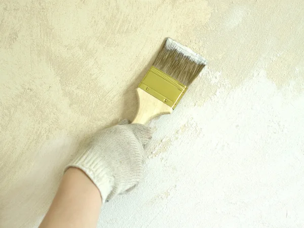 Woman's hand in glove with brush paint wall — Stock Photo, Image