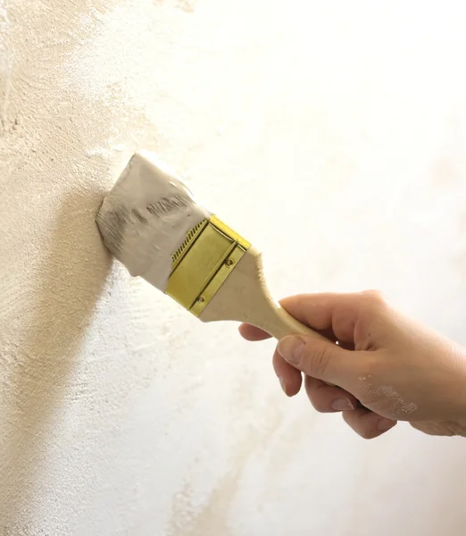 Mano de mujer con pincel pintado de pared — Foto de Stock