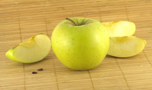 Pomme avec des morceaux sur tapis en osier — Photo