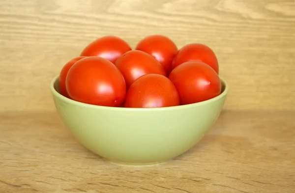 Tomatoes in bowl on wood — Stock Photo, Image