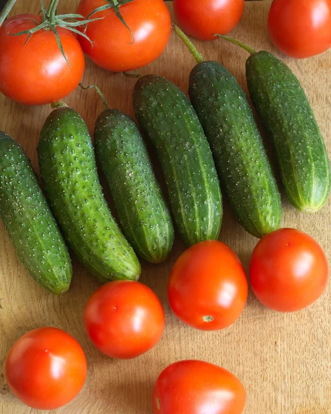 Cucumbers and tomatoes on kitchen table — Stock Photo, Image