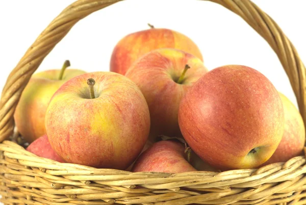 Red and yellow ripe apples in brown wicker basket isolated — Stock Photo, Image