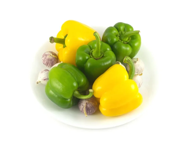 Peppers and garlic on white plate isolated close up — Stock Photo, Image