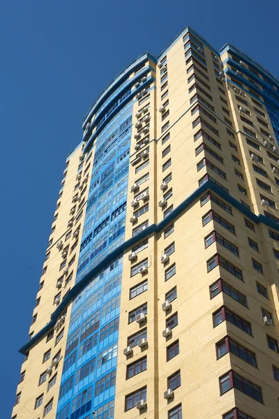High yellow modern multi-storey building on blue cloudless sky vertical view — 스톡 사진