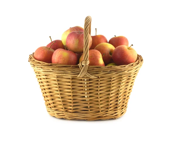 Dojrzałe jabłka w wiklinowym koszu na białym tle — Zdjęcie stockowe