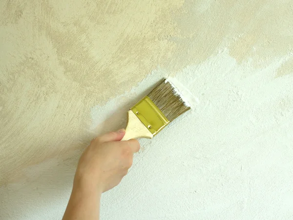 Mano de mujer con pincel pared de pintura — Foto de Stock