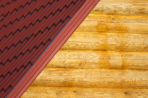 Houten huis muur en een deel van de rode dak van metaal tegel close-up — Stockfoto