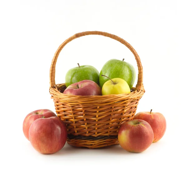 Viele reife Äpfel in braunem Weidenkorb und in seiner Nähe isoliert — Stockfoto