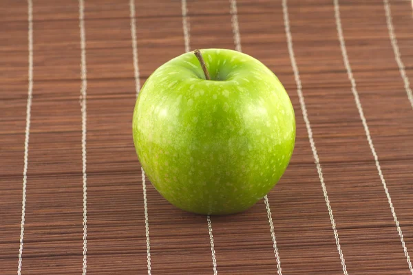 Ripe apple on brown wicker straw mat close up — Stock Photo, Image