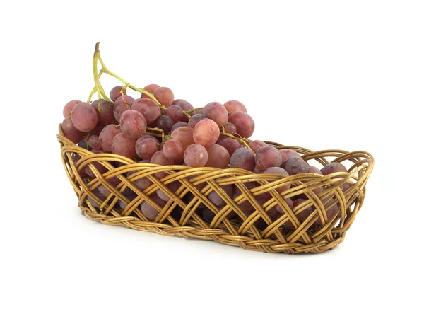 Uva vermelha no ramo em cesta de vime de palha isolada — Fotografia de Stock
