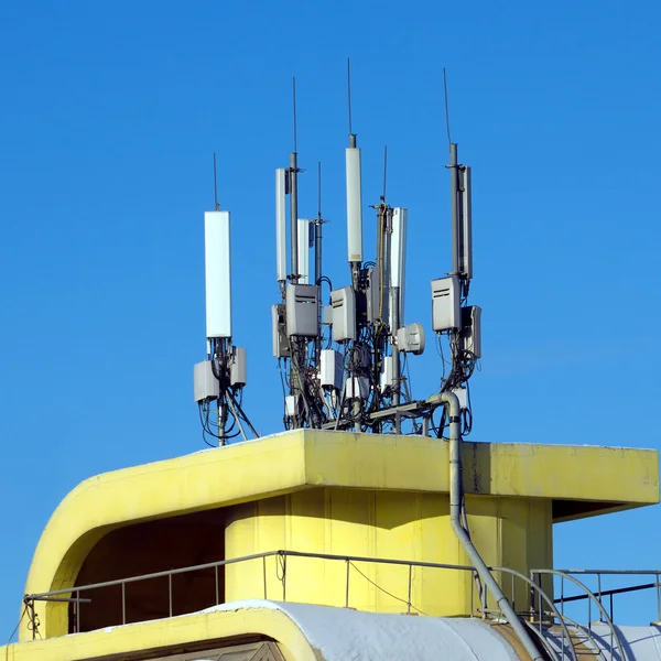 De nombreuses antennes électroniques sur le toit jaune du bâtiment — Photo