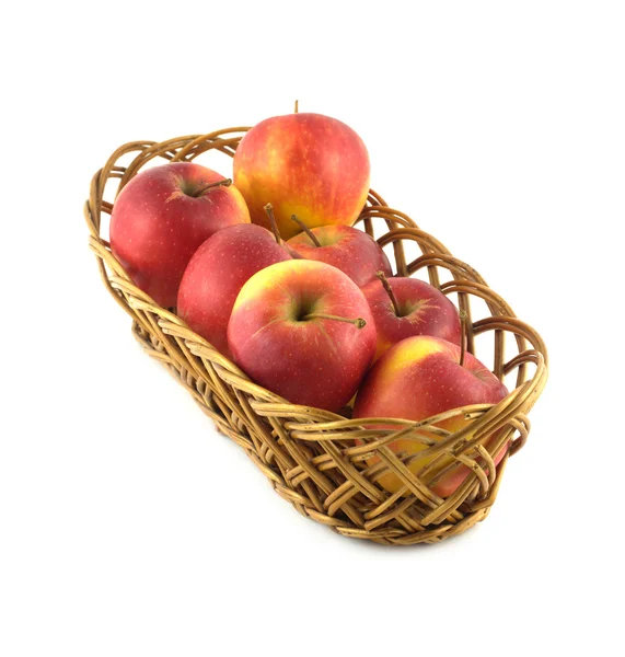 Спелые красные яблоки в длинной коричневой плетеной корзине изолированы — стоковое фото