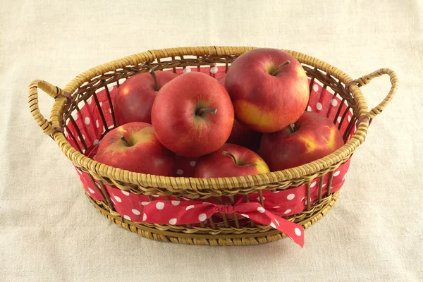 Manzanas rojas maduras en canasta larga de mimbre marrón sobre tela beige —  Fotos de Stock