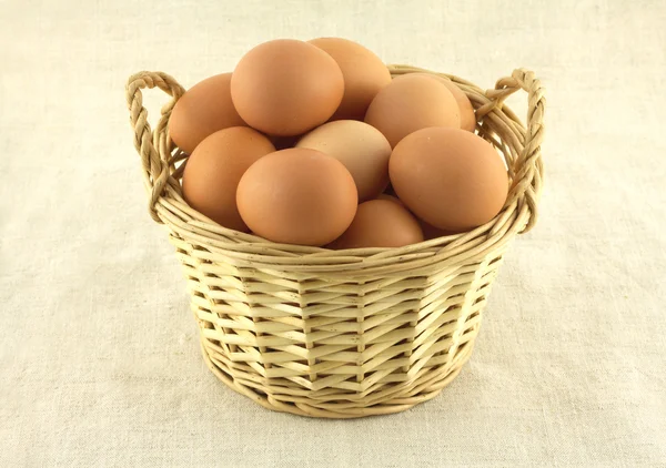 Chicken eggs in wicker basket on beige cloth isolated — Stock Photo, Image