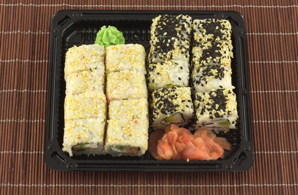 Sushi rolky v nádobě z plastu na proutěný slaměné rohože closeup — Stock fotografie