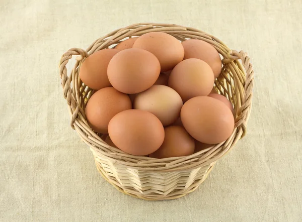 Jaja kurze w wiklinowym koszu na beżowe tkaniny na białym tle — Zdjęcie stockowe