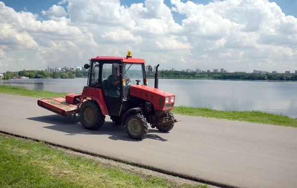 Trator move-se para baixo em uma estrada contra a paisagem da cidade — Fotografia de Stock