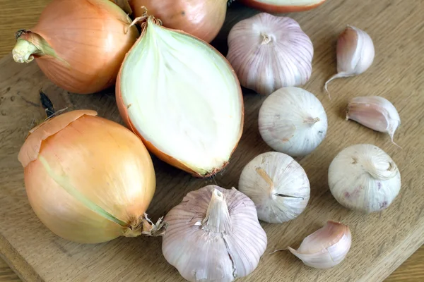 Onion and garlic on kitchen board closeup — Stock Photo, Image