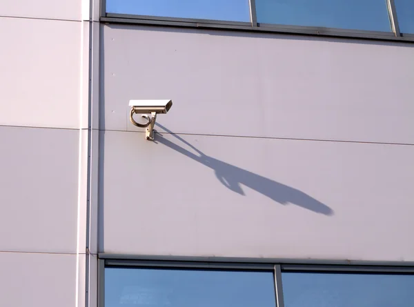 Câmera de segurança na parede do edifício com sombra longa — Fotografia de Stock