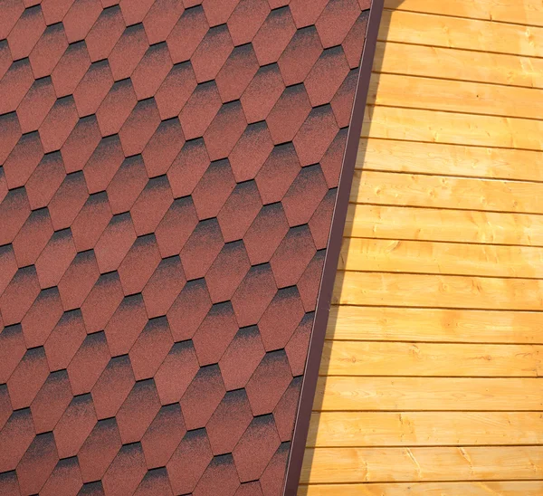 Houten huis muur en een deel van de rode dak van zachte tegel close-up — Stockfoto