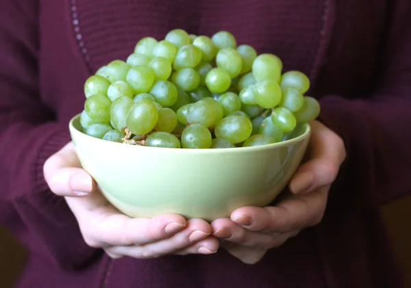 Mãos femininas segurar tigela com uvas verdes apetitosas — Fotografia de Stock