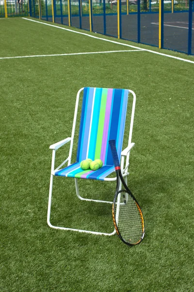 Кресло, теннисная ракетка и четыре мяча на корте — стоковое фото