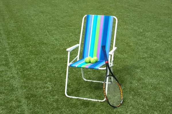 Sillón, raqueta de tenis y cuatro bolas en la cancha — Foto de Stock