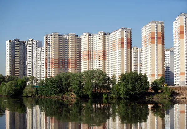 Geconstrueerd kudde van flats over rivier en heldere blauwe hemel in zomerdag — Stockfoto