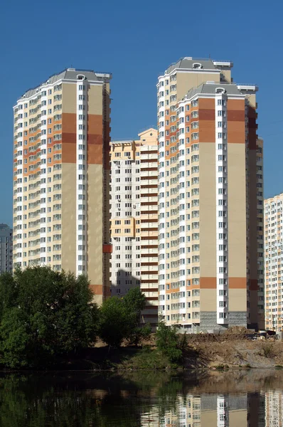 Muitos blocos de apartamentos sobre o rio e céu azul claro — Fotografia de Stock