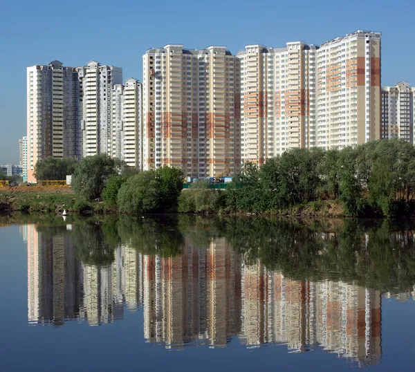 Geconstrueerd blok van flats over rivier en heldere blauwe hemel in zomerdag — Stockfoto