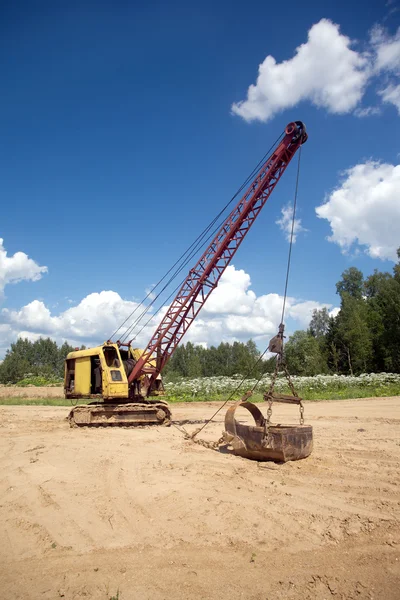 Grävmaskin står på sand nära skogen sommardag — Stockfoto